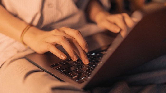 Close-up of hands typing on a laptop in warm evening light