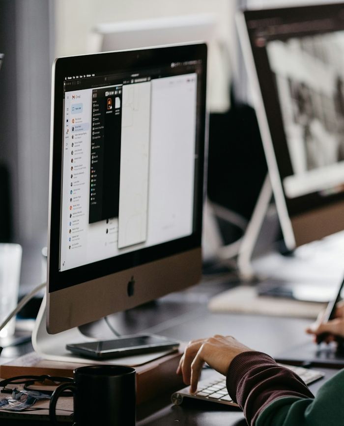 A designer's hands sketching on a graphics tablet, with design software open on a desktop monitor